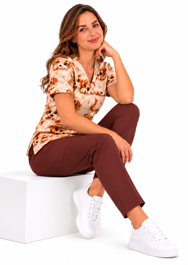 Damen-Kasack „Kleine Pfoten“ mit Welpenmotiv am sitzenden Model, kombiniert mit brauner Hose und weißen Schuhen.